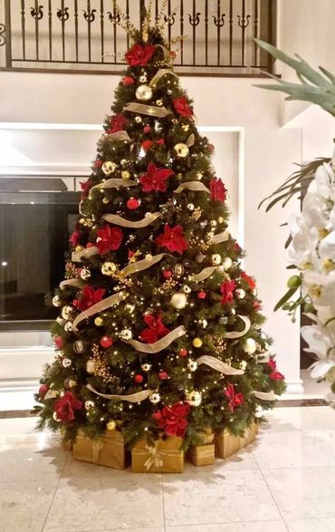 Luxury red magnolia flower, gold berries and gold ribbon 11 foot Christmas tree in entrance.