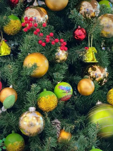 Closeup of green and gold Chrismtas decoration s with hints of silver + red & green berries & bells.