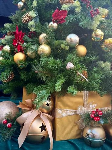 Closeup bauble spiral tree with red Christmas flowers and luxury Christmas present bye with bells.