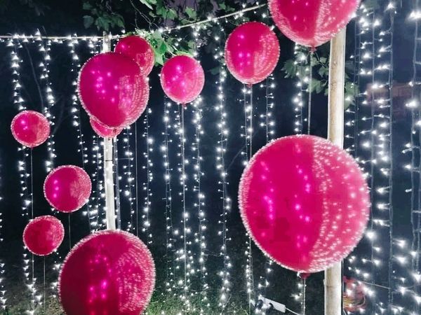 Stand-alone fairy light wall with red helium balloons.