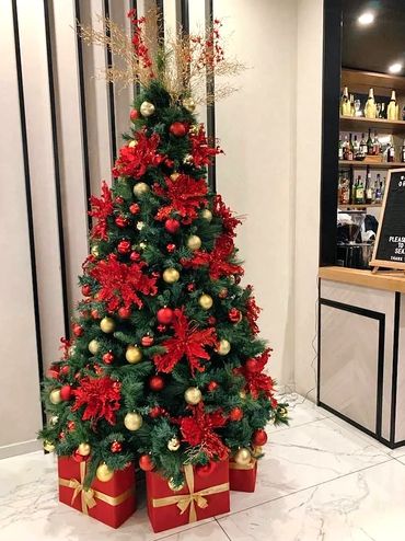 Big red flowers and gold decorations on hotel Christmas tree.
