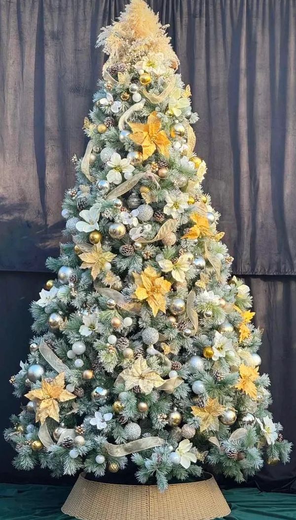Professional decorations on luxury white and gold Christmas tree with poinsettia and birds.