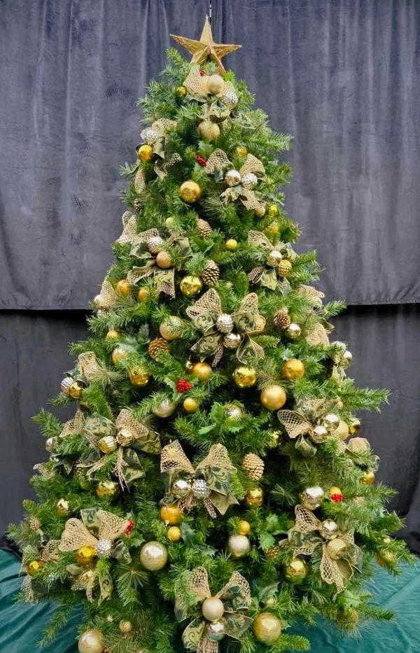 Fancy handmade green and gold Christmas bows on decorated Christmas tree with gold star topper.