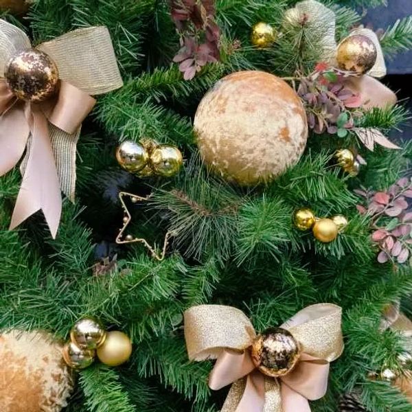 Closeup of large velvet baubles and satin gold bows with textured bauble centre on Christmas tree.