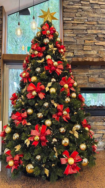 Handmade bauble bow Christmas tree with bright red wire edged ribbon, gold leaves on 10 ft tree/