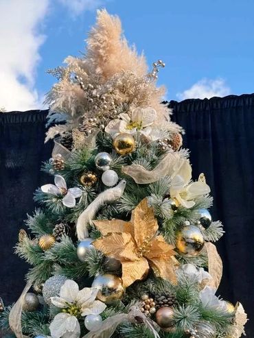 Closeup of luxurious Christmas tree topper featuring pampas grass, gold berries, birds and flowers.