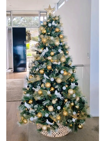 White dove and gold ribbon Christmas tree on flocked snow tipped artificial pine tree.