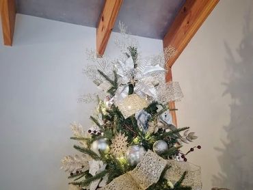 Closeup of Christmas tree topper with fancy mesh ribbon, berries, snowflakes and poinsettia.