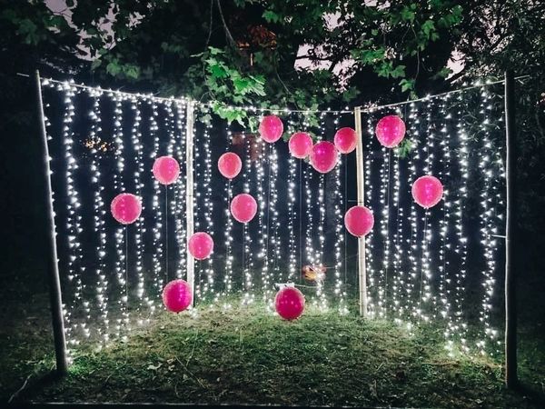 Stand-alone fairy light wall with red helium balloons.