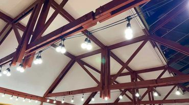 Bright white festoon lights on ceiling to light up catering area for private function at old church.