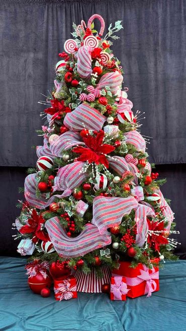 Fancy candy cane Christmas tree decorations with big mesh stripy ribbon and present stack.