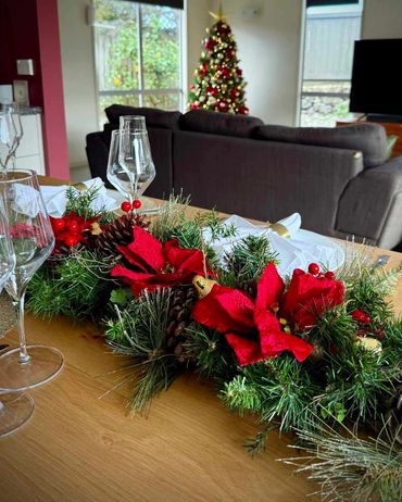 Traditional red poinsettia and natural elements on dining table centrepiece for mid winter Xmas.