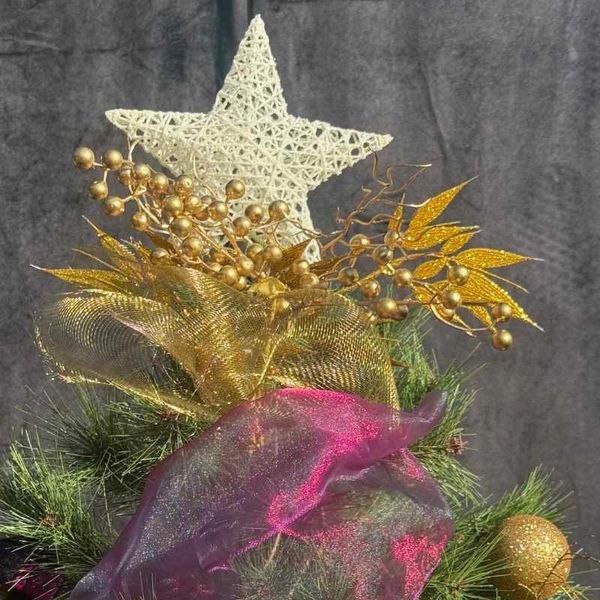 Closeup of artistic star topper with metal gold mesh ribbon and sheer purple ribbon.