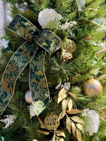 Closeup of Christmas tree decorations featuring ribbon, preserved flowers, glass baubles and roses.