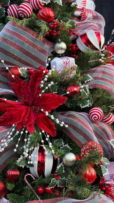 Closeup of poinsettia flower and other decorations on fun candy themed Christmas tree.