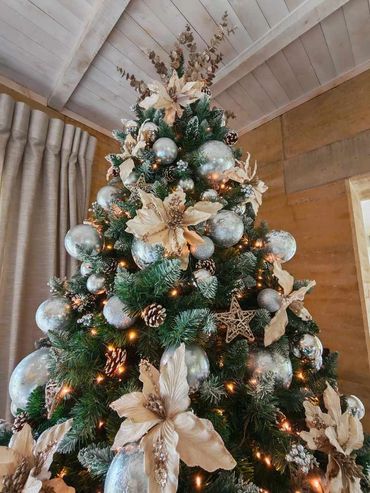 Top of silver & champaign Christmas tree on snow tipped artificial pine tree + frosted baubles.
