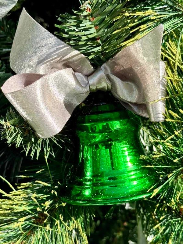 Closeup of green and silver decorations with large stars on 10 foot tall Christmas tree.