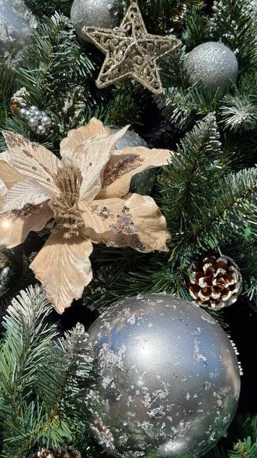 Closeup of silver mercury baubles, star & velvet poinsettia flower on our luxurious Christmas tree.