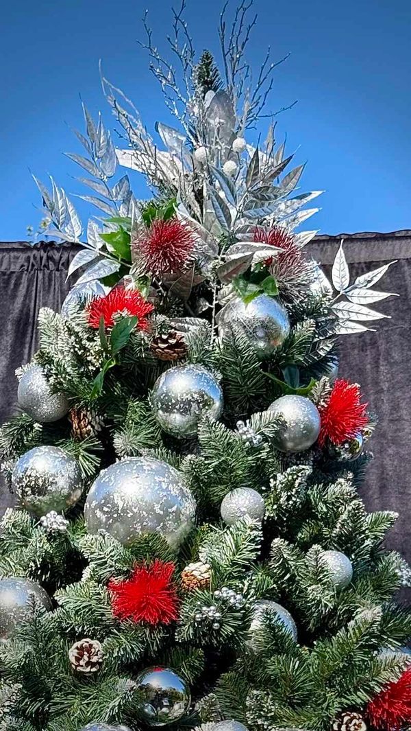 Closeup of artistic Christmas tree topper featuring silver branches and Pohutakawa flowers.