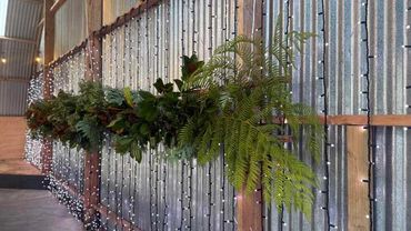 Fern and foliage garland plus fairy light curtain for indoor wedding.