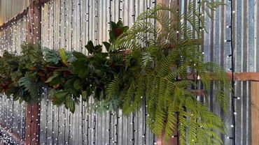Fern and foliage garland plus fairy light curtain for indoor wedding.