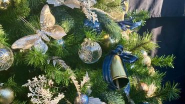 Closeup of Christmas tree decorations featuring cow bells with blue bows, gold butterflies &baubles.