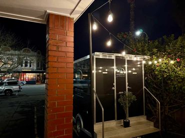 Classic festoon lights with black poles outdoors for private function.