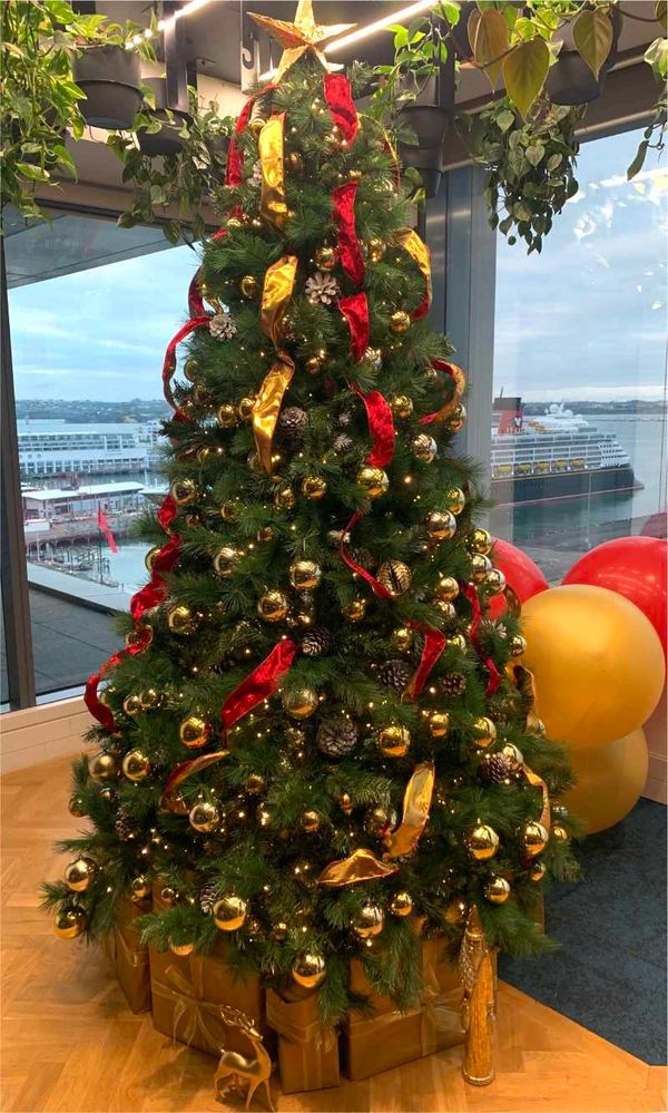 Velvet ribbon, metallic baubles and frosted pinecones on Christmas tree at end of year party.