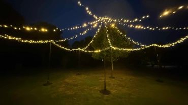 Outdoor fairy light canopy with black poles and commercial grade fairy lights in warm white.