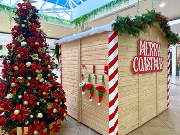 Traditional look Santa grotto featuring red and gold thumbing with fun details at Coast Plaza 2025.