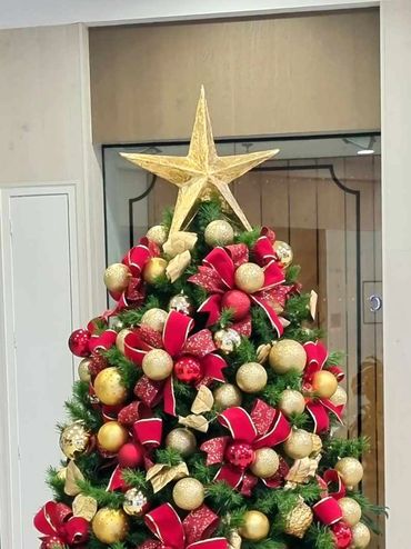 Closeup of hand-made star topper with gold leaf coating on luxury Christmas tree.
