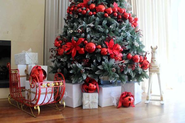 Luxury present stack around red spiral Christmas tree with sleigh, bells and rocking horse.
