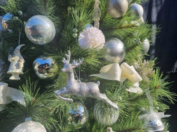 Closeup of reindeer decoration and satin bow on realistic 7 foot pine tree.