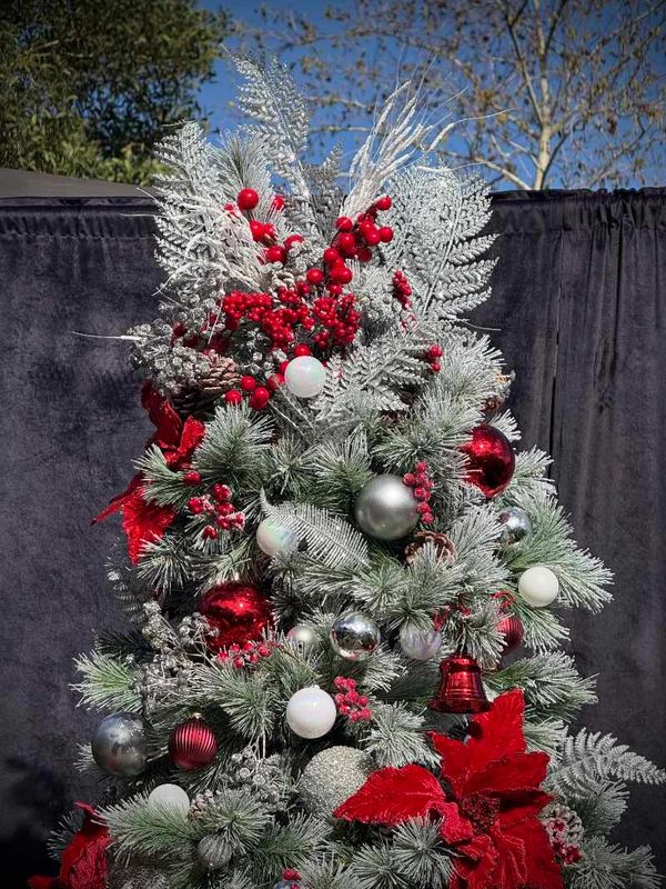 Closeup of Silver Fern and red berry Christmas tree topper on frosted look Christmas tree.
