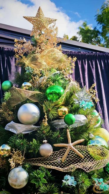 Closeup of coastal themed Christmas tree featuring golden starfish and fishing net style ribbons.