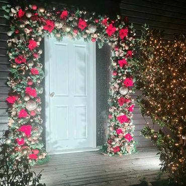 Giant door garland with warm white fairy light in tree beside.