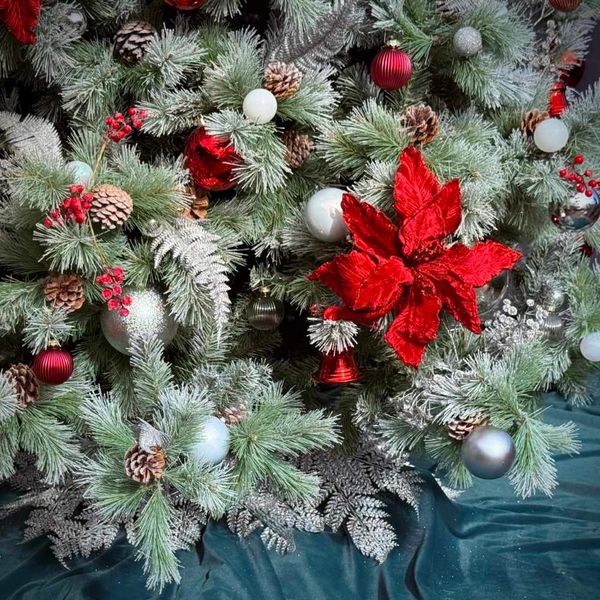 Closeup of red, silver, and white Christmas tree decorations on realistic snowy pine tree.