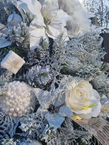 Closeup of white decorations on realistic flocked snowy Christmas tree.