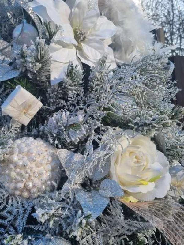 Closeup of white decorations on realistic flocked snowy Christmas tree.