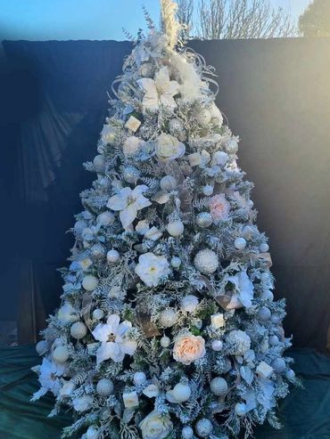 White flocked luxury Christmas tree with peach ribbon and peacock topper.
