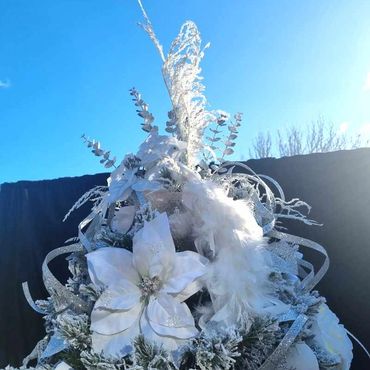 Closeup of fancy silver and white peacock Christmas tree topper with pampas grass.