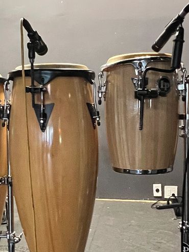 A set of conga drums with microphones in a music studio.
