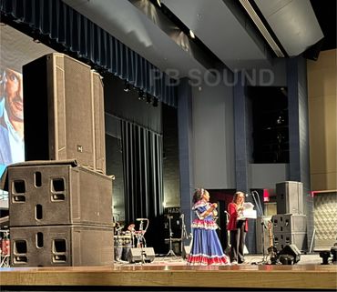 Two women on stage during an event, one in a colorful traditional dress.