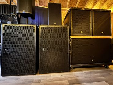 A collection of large black RCF speakers and sound equipment in a room.