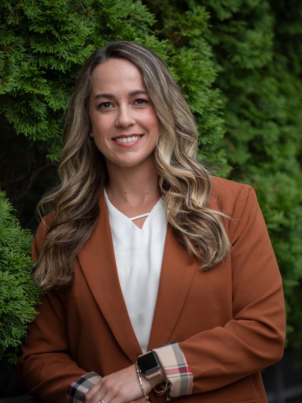 Confident woman in a rust-colored blazer smiling outdoors.