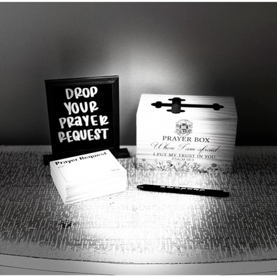 A prayer request station with cards, pen, and a prayer box on a table.