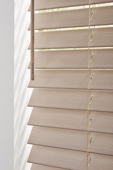 Close-up of beige horizontal window blinds with a wooden adjustment stick.