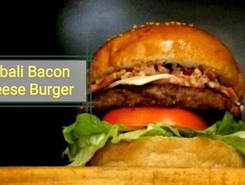 Close-up of a Bali Bacon Cheese Burger with lettuce and tomato.
