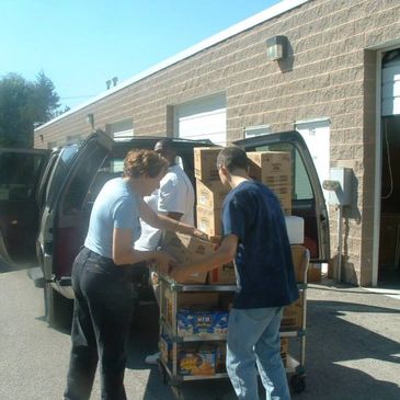 Volunteers removing boxes of donations from a car