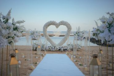 Beach wedding setup with heart-shaped floral arch.